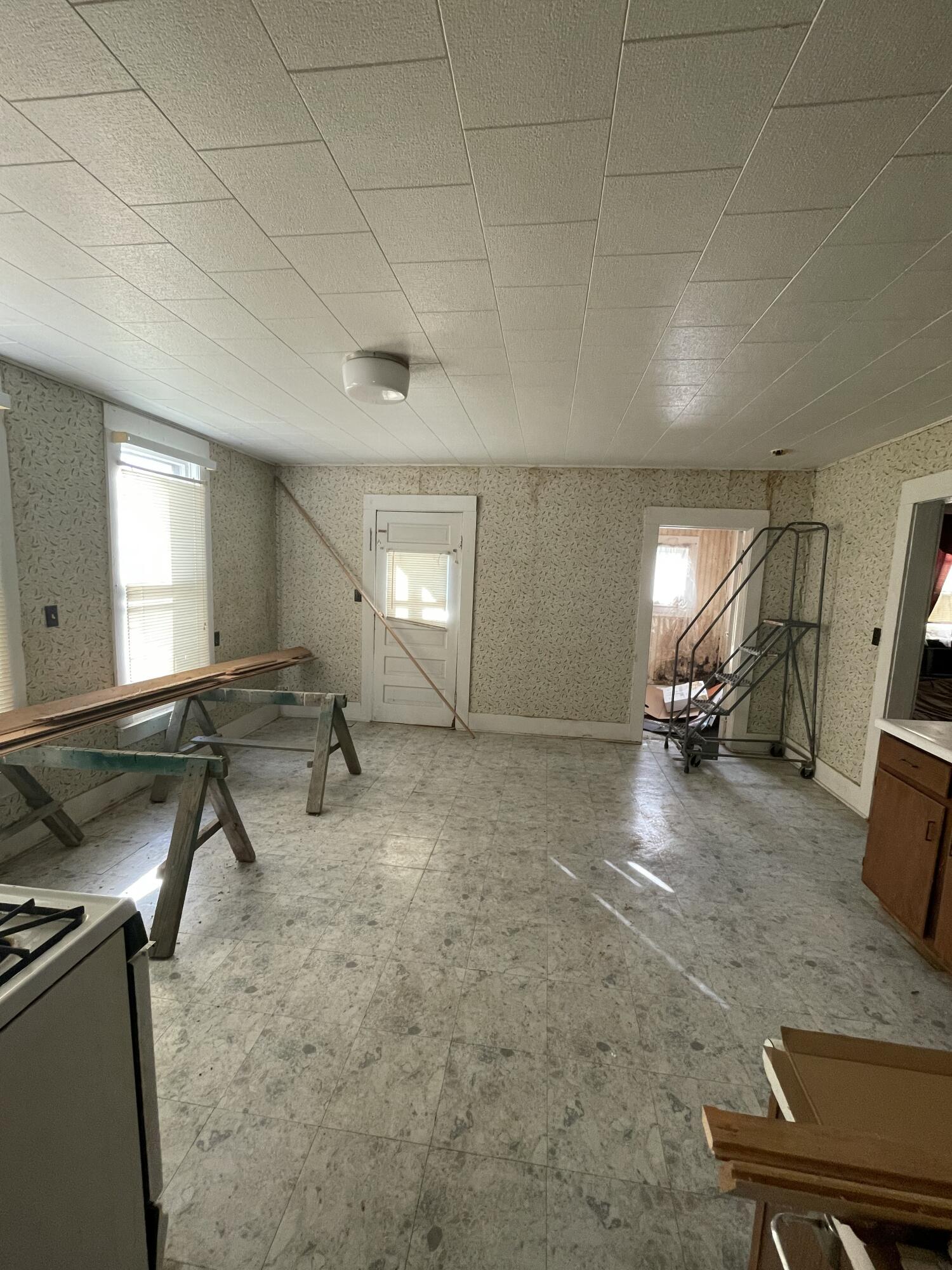 Kitchen with patterned walls, gray tile floor, and renovation materials on sawhorses.