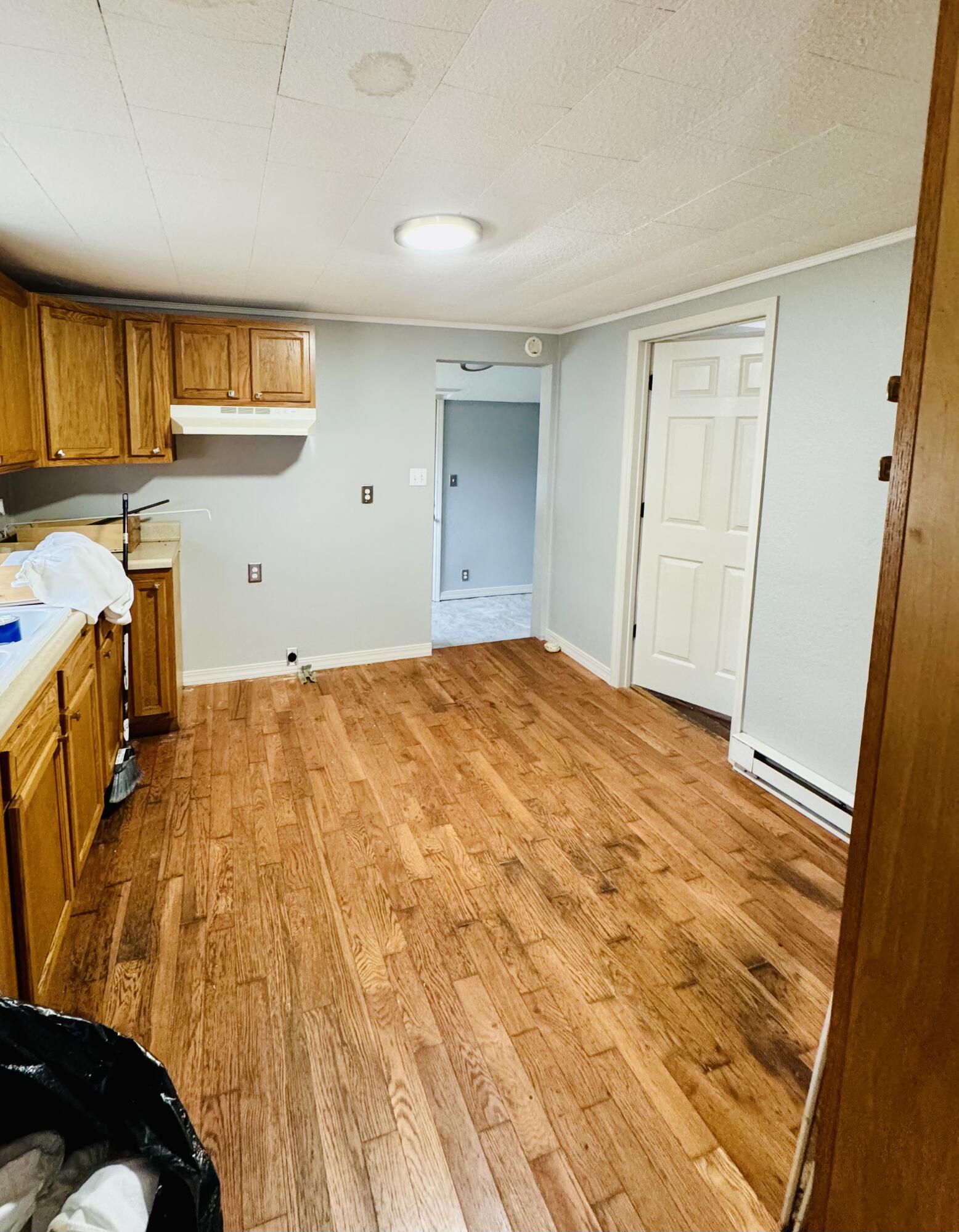 Kitchen with honey-colored cabinets, a white range hood, and wood-look flooring.