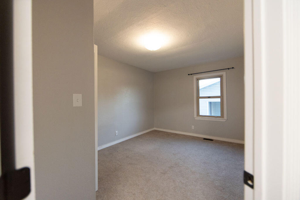 Unfurnished room with beige carpet, gray walls, and a single window.
