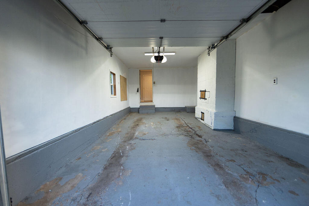 Empty garage with a raised overhead door and a worn concrete floor.