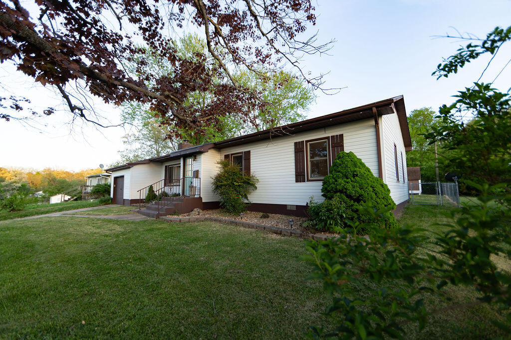 Single-story white house with brown trim, a small covered entry, and a broad lawn.