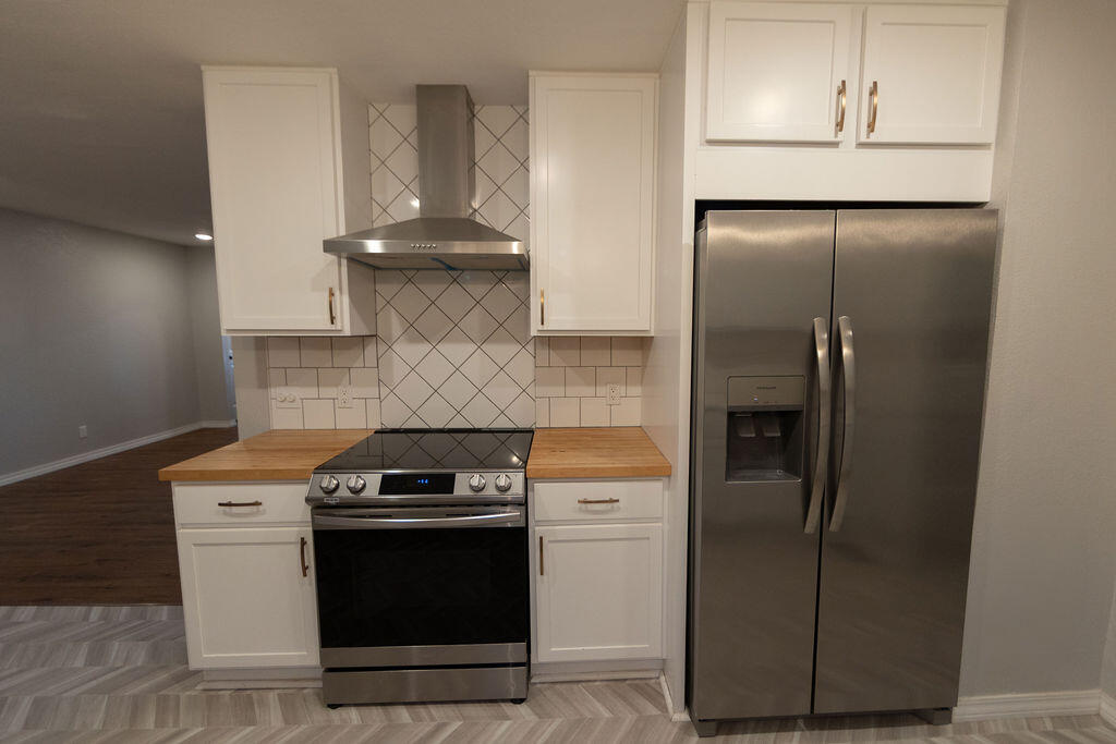 Kitchen with white cabinets, butcher-block counters, and stainless steel appliances.