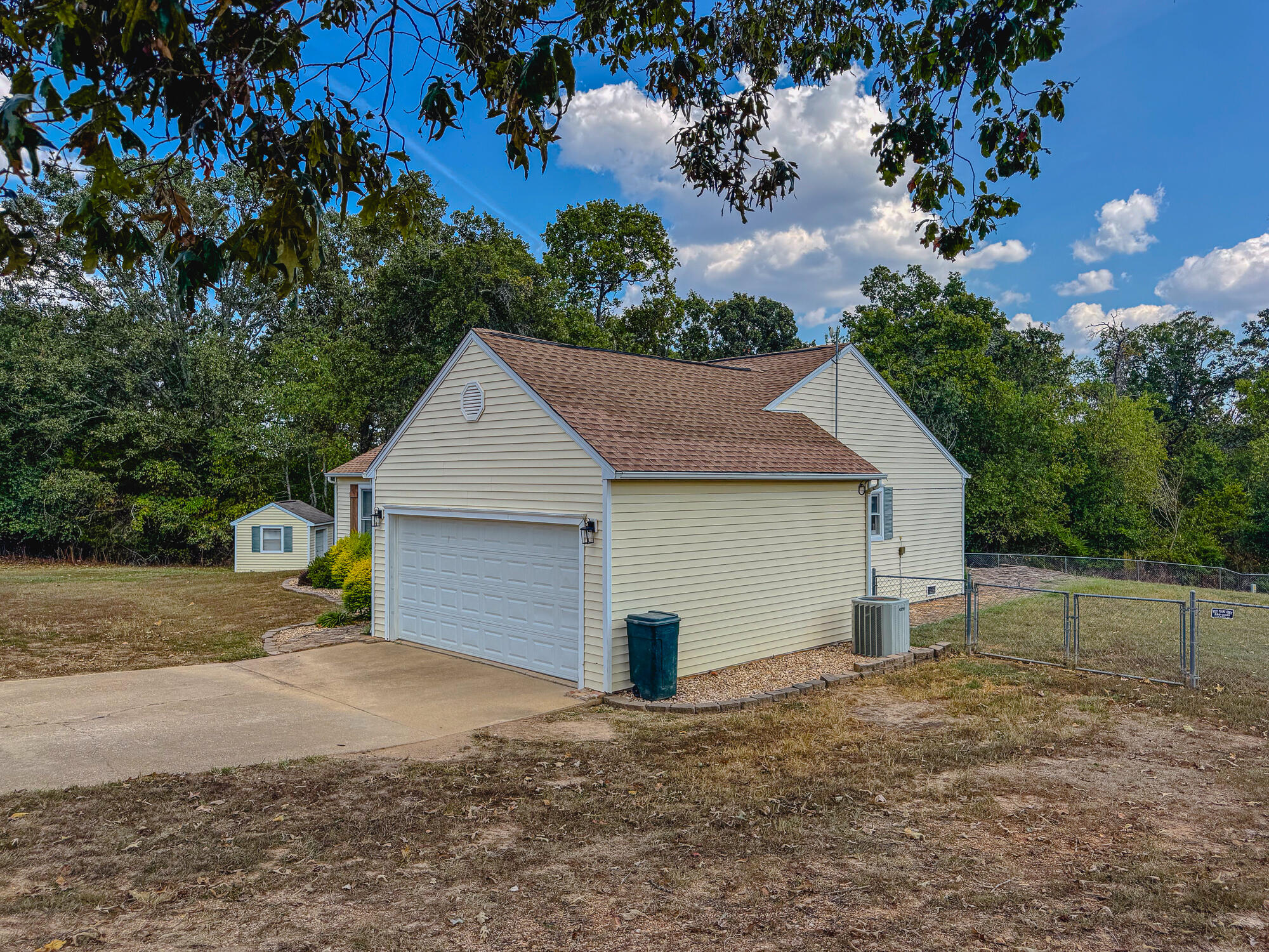 Beige home with a large attached garage, concrete driveway, and fenced side yard.
