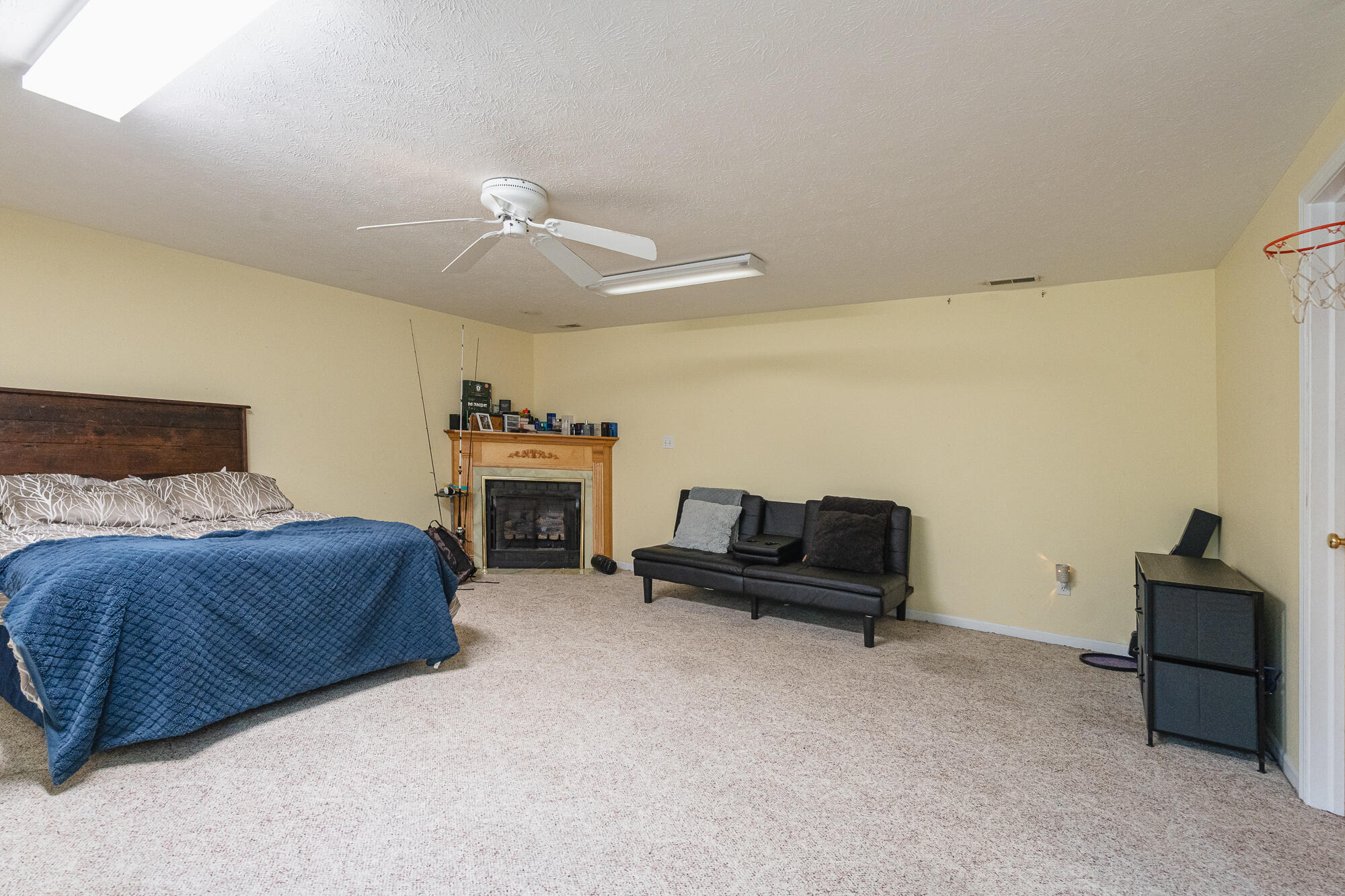 Bedroom with a blue-covered bed, fireplace, and black loveseat.