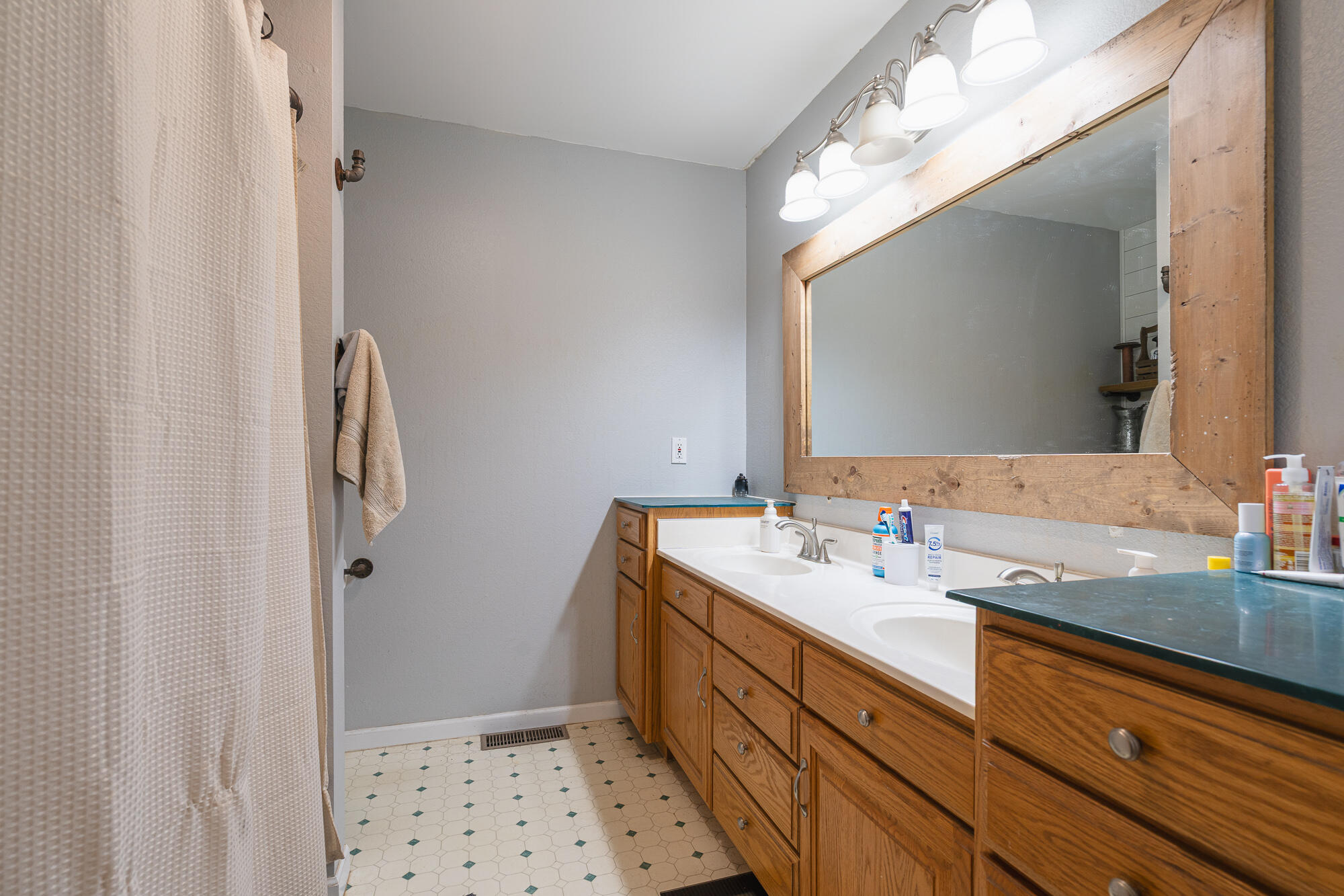 Bathroom with a long wooden double vanity, two sinks, and a large wood-framed mirror.