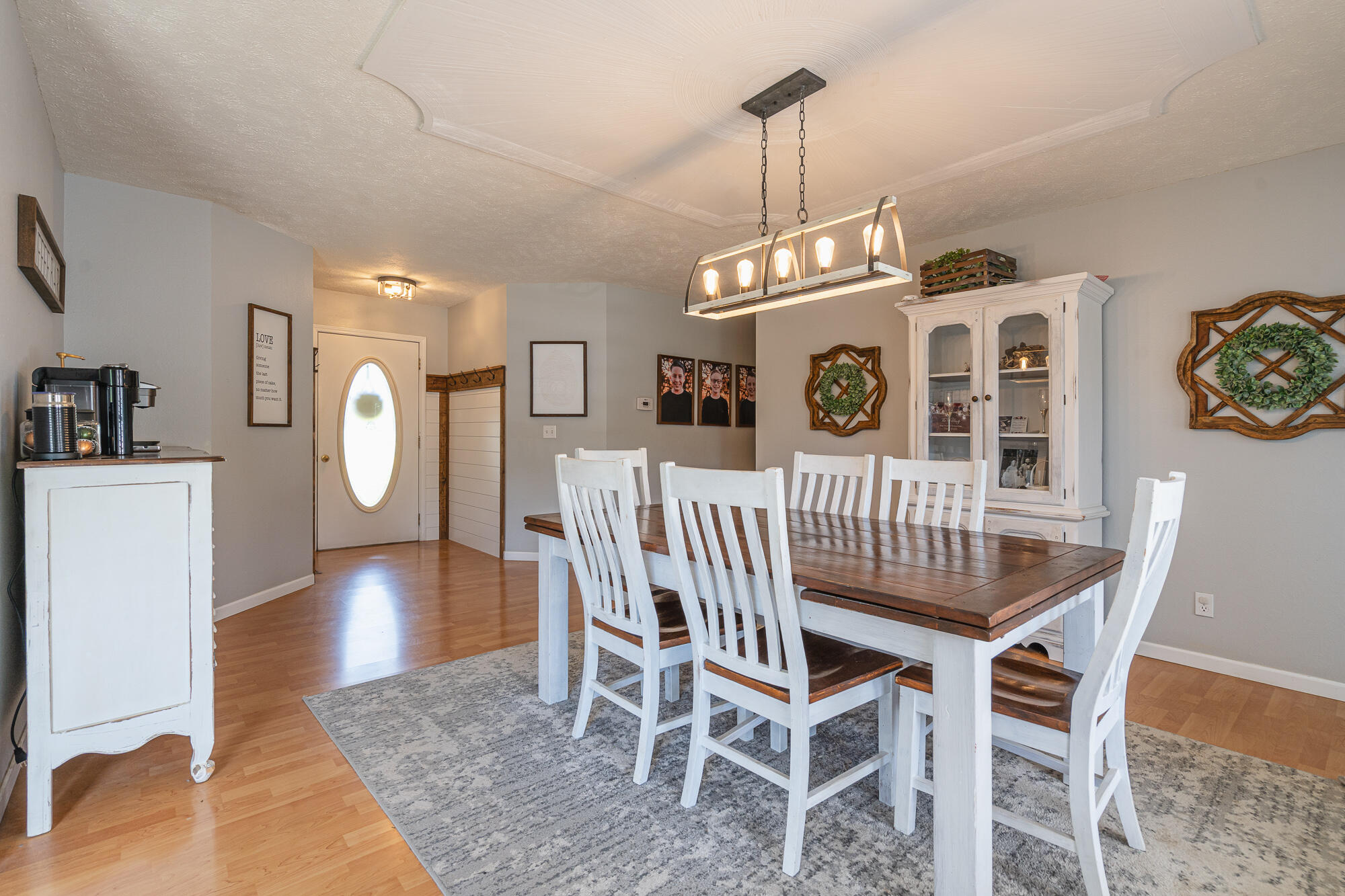 Dining room with a dark wood table, white chairs, and a prominent linear chandelier.
