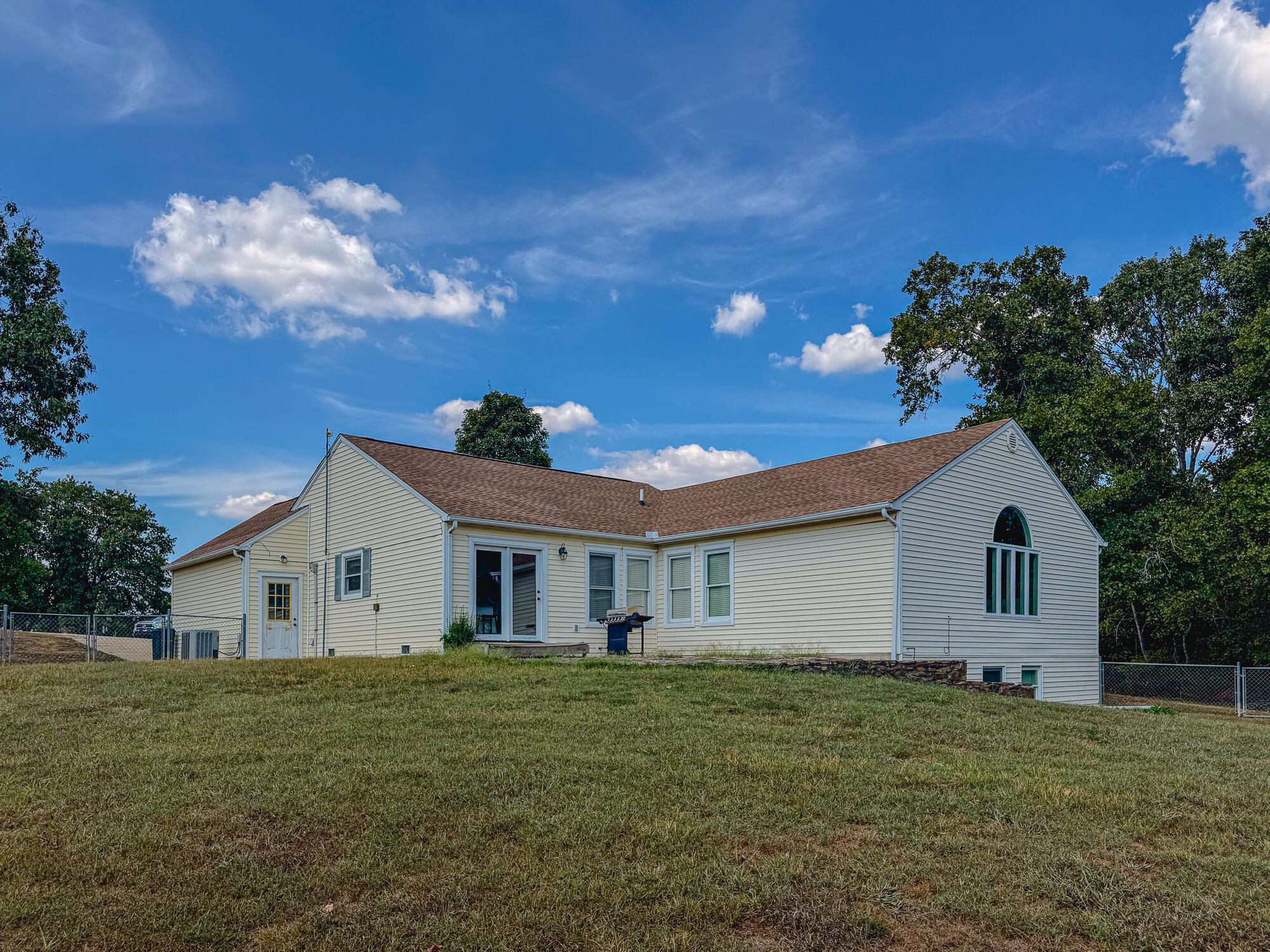 House exterior with a broad grassy lawn, sliding glass door, and distinctive arched window.