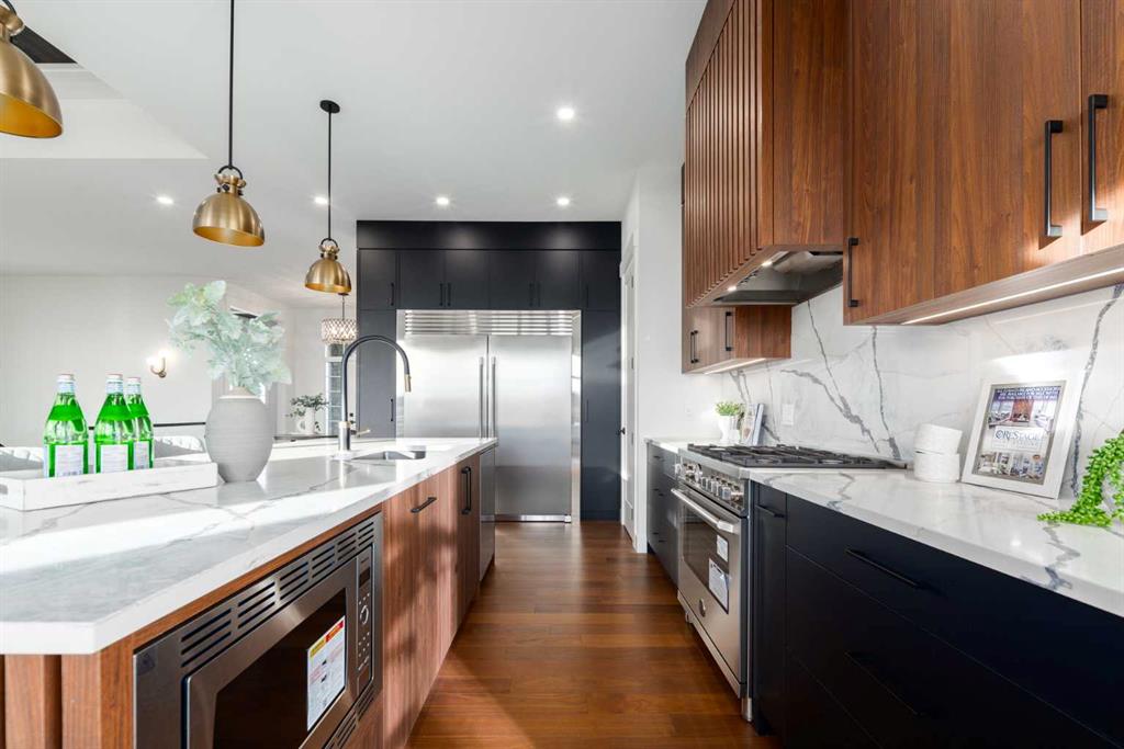 Modern kitchen with a marble island, wood cabinetry, and stainless steel appliances.