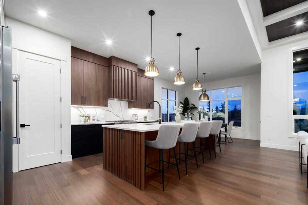 Modern kitchen with walnut cabinetry, marble island, and upholstered bar stools.