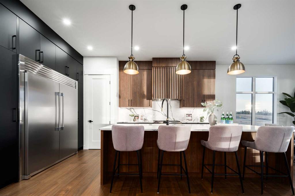 Modern kitchen with a dark wood island, four upholstered stools, walnut cabinetry, and stainless steel refrigerator.