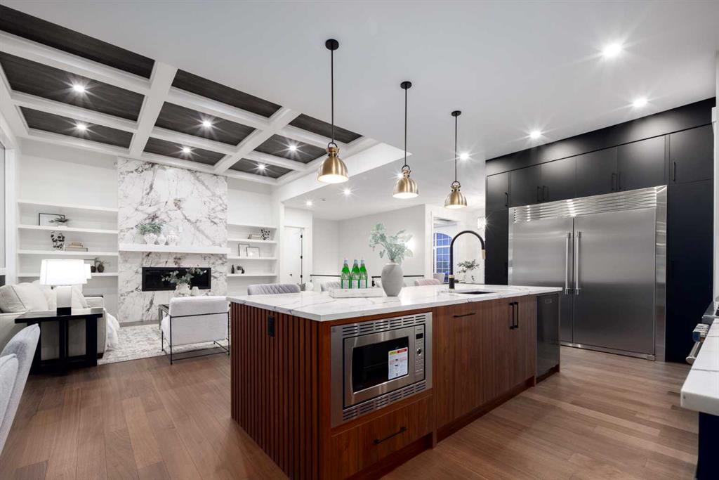 Open-concept kitchen with a large wood island, stainless appliances, and a marble fireplace.