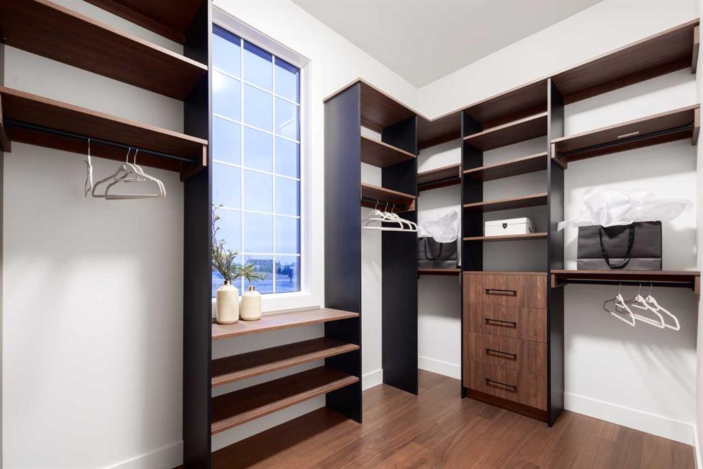 Walk-in closet with dark wood shelving, central drawers, and shoe shelves beneath a tall window.