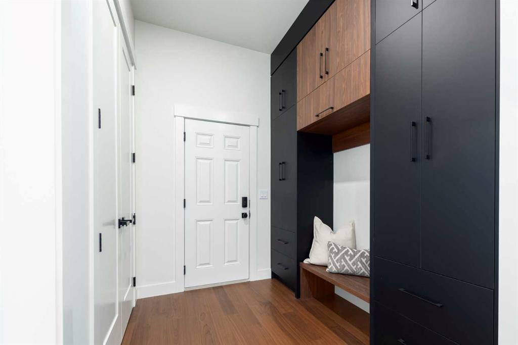 Entryway with dark built-in storage, a wood bench, and a white front door.