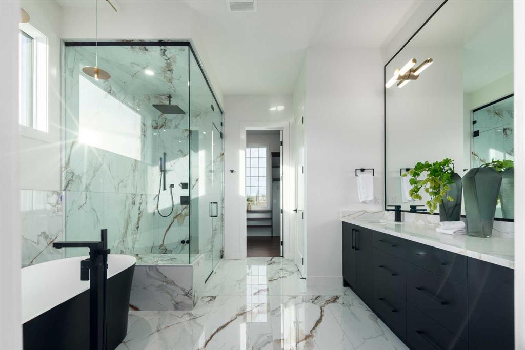 Modern marble bathroom with a glass shower, freestanding tub, and dark vanity.
