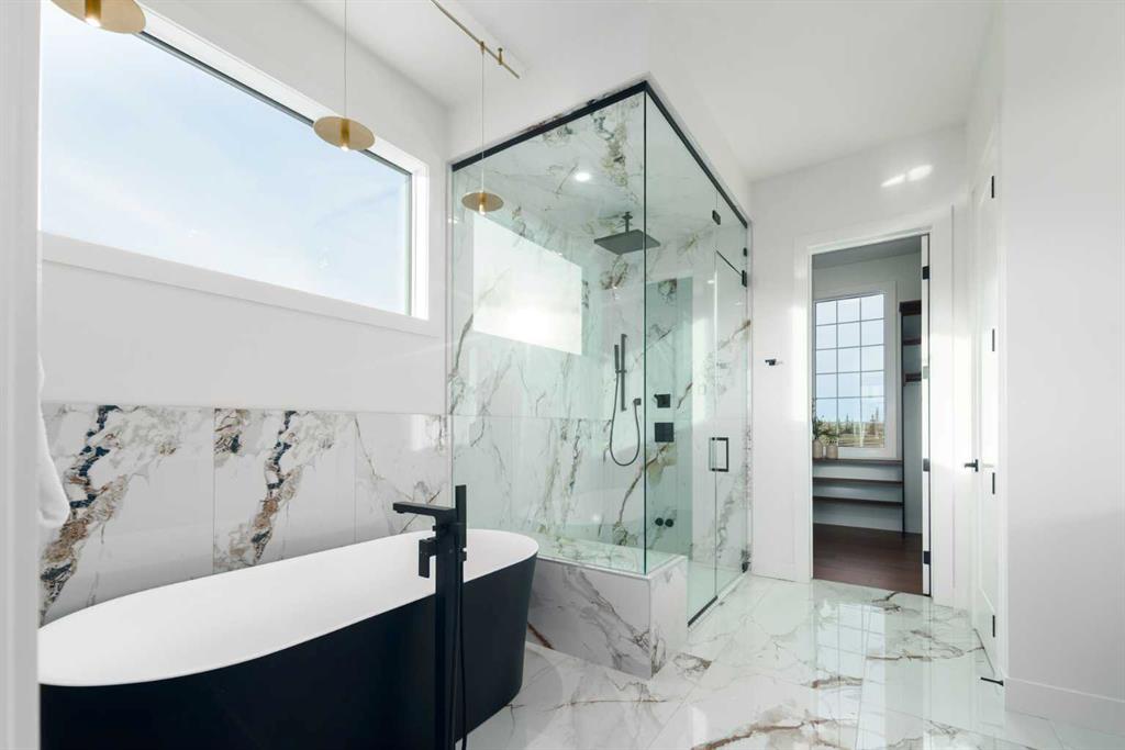 Modern bathroom with a freestanding tub, glass shower, and veined marble-look tile.