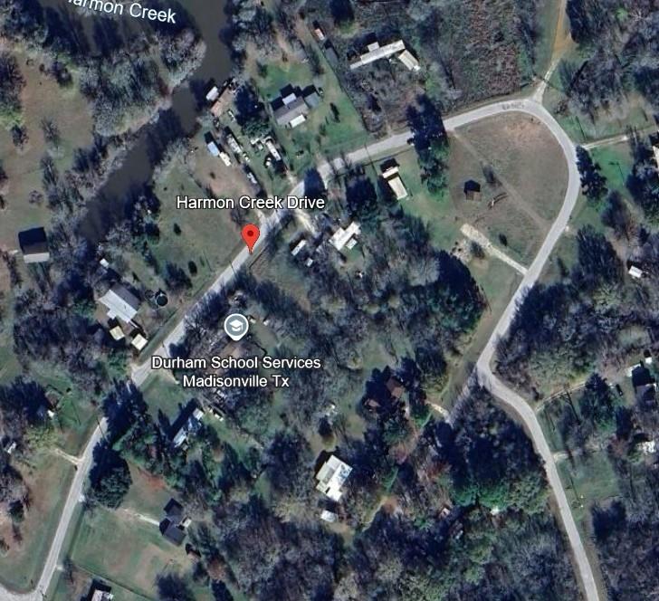 Aerial view of a wooded lot marked by a red pin along Harmon Creek Drive, near Durham School Services.