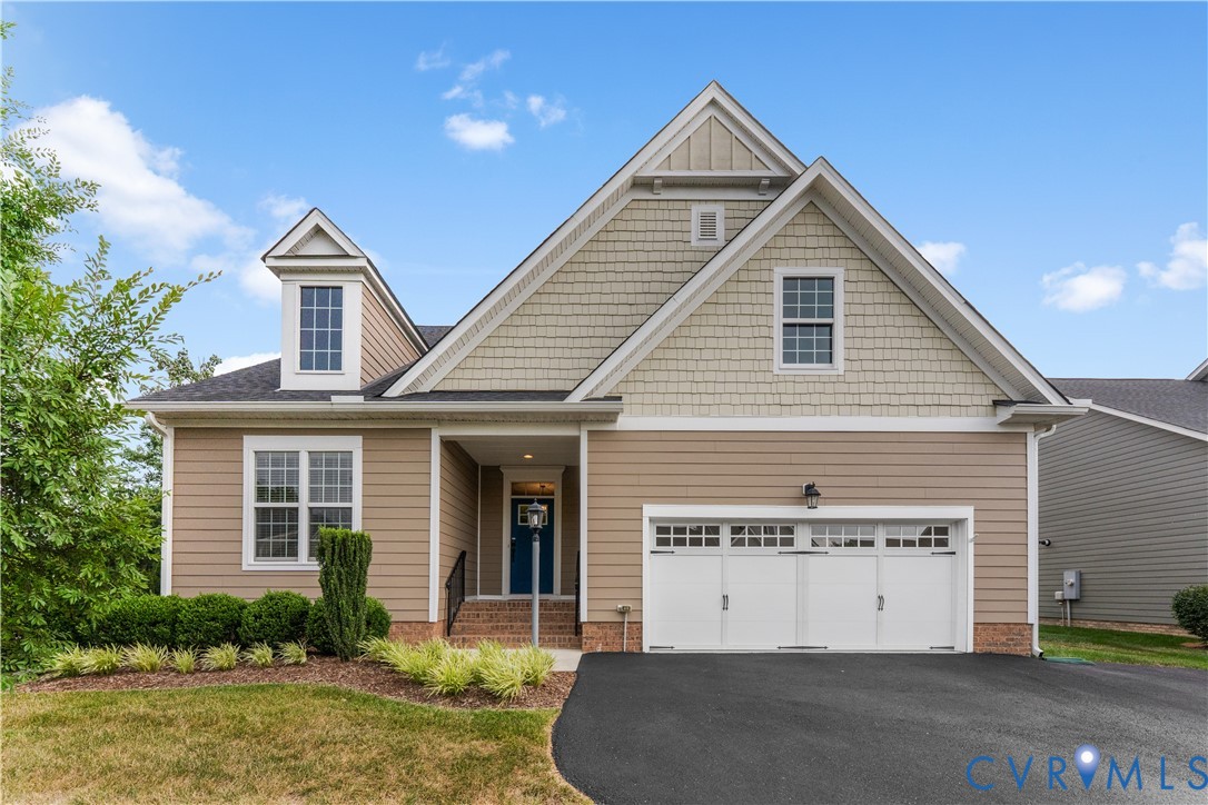 House exterior with steep gables, a white double garage door, and landscaped front yard.
