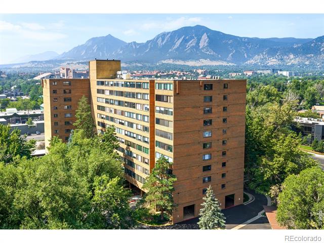Brick apartment building among trees, with mountains rising behind the city.