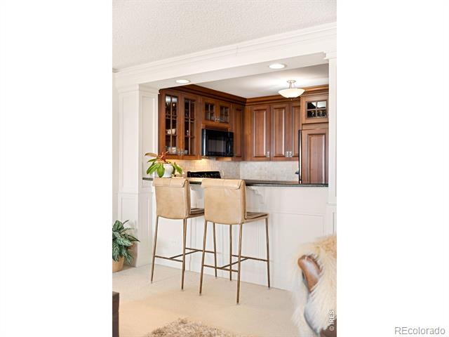 Kitchen with rich wood cabinetry and a breakfast bar with two upholstered stools.