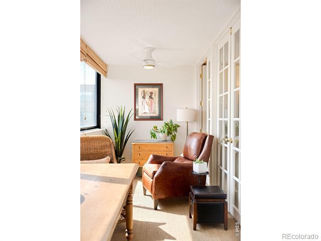 Furnished sitting area with a brown leather armchair, potted plants, and white French doors.