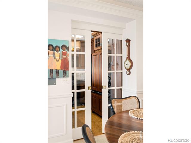 Dining area with a round wooden table, open French doors, and a pendulum clock.