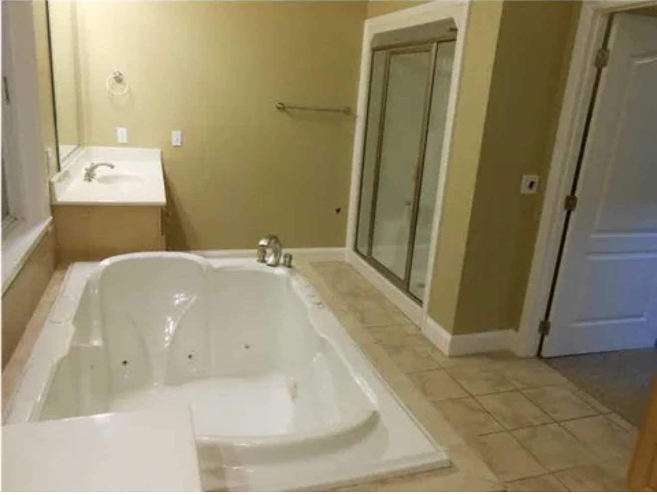 Bathroom with a large jetted tub and separate glass-enclosed shower.