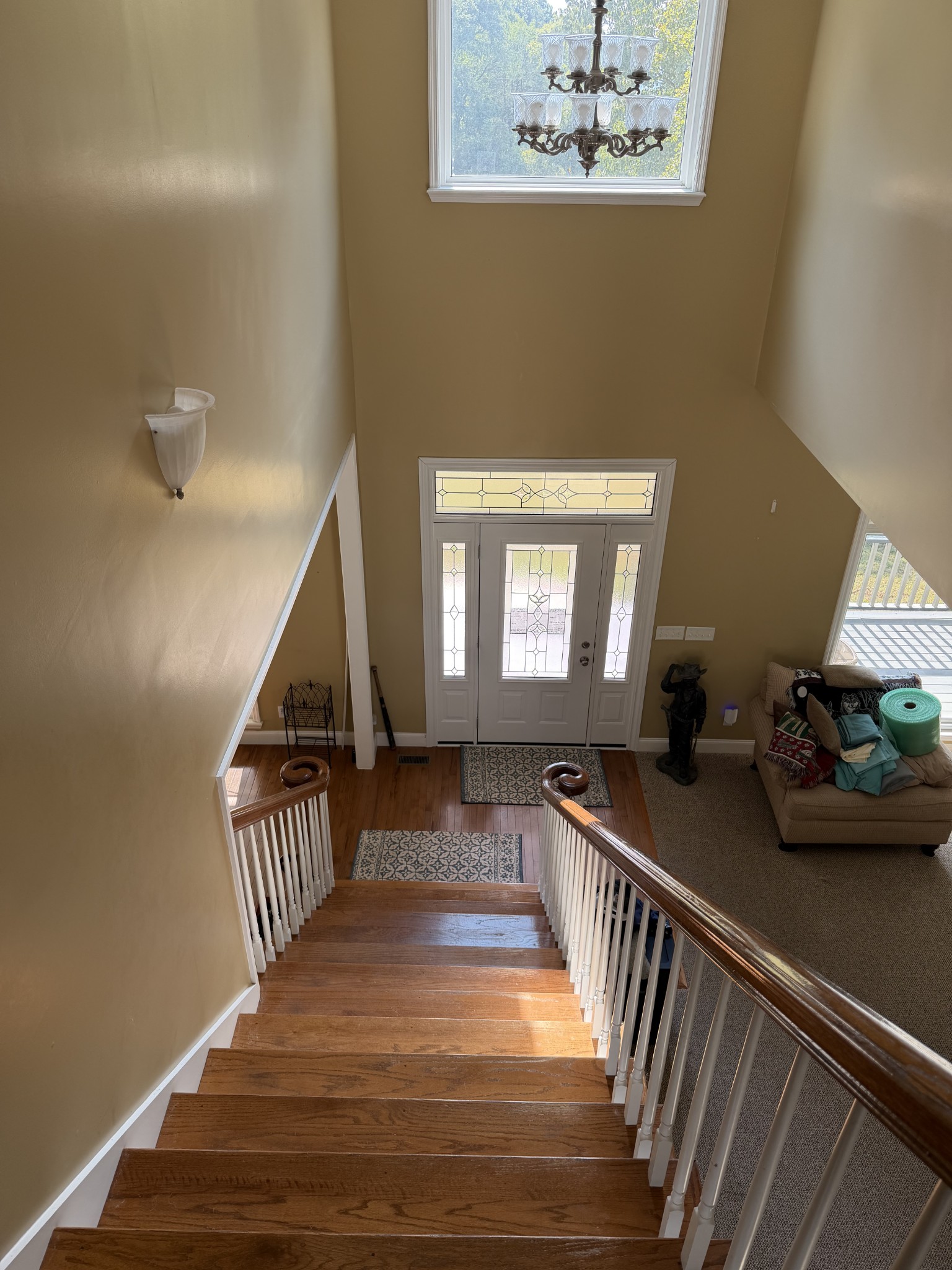 Foyer staircase overlooking a decorative-glass front door, with hardwood steps and a chandelier.