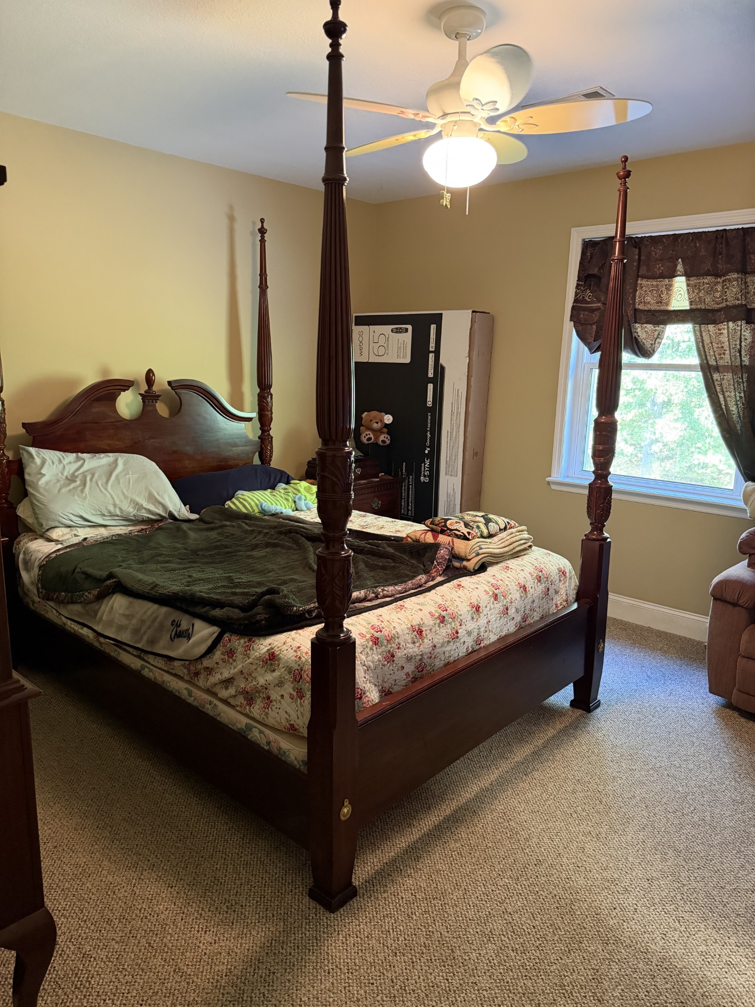 Bedroom with a dark wood four-poster bed, floral bedding, and a curtained window.
