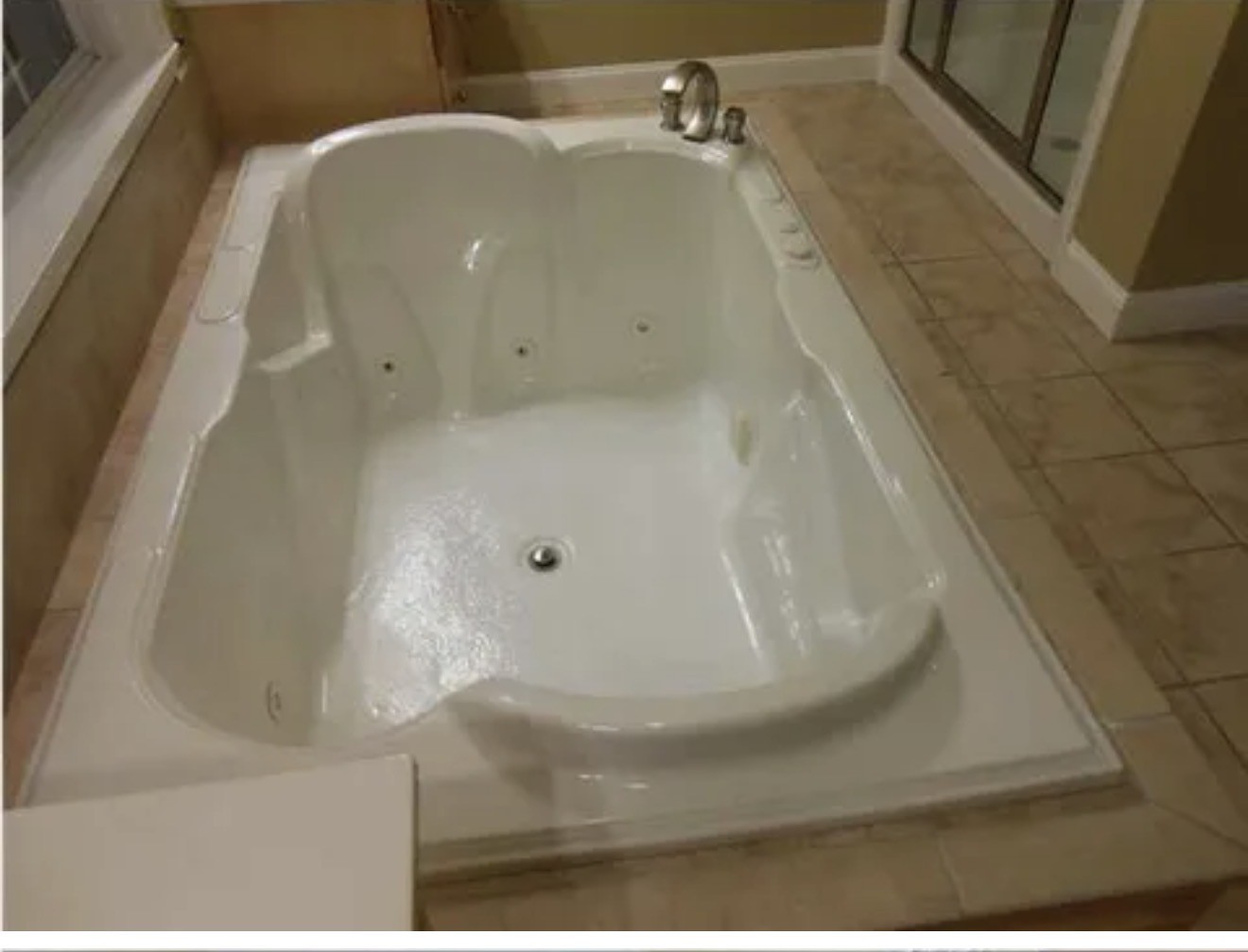 Jetted bathtub with a chrome faucet beside a glass shower enclosure.