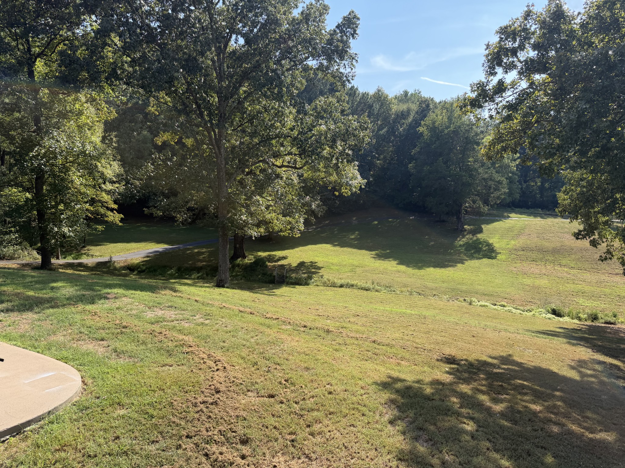 Grassy property lawn with mature trees and a paved path curving through the grounds.