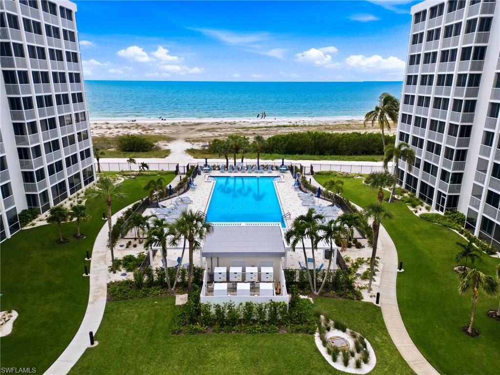 Beachfront condominium pool framed by two towers, with landscaped grounds and ocean beyond.