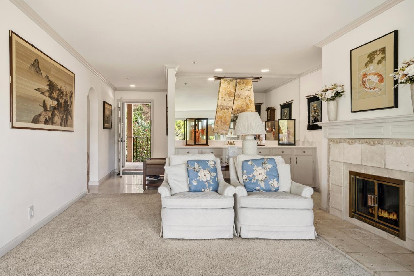Living room with white armchairs, blue floral pillows, built-in cabinetry, and a tiled fireplace.