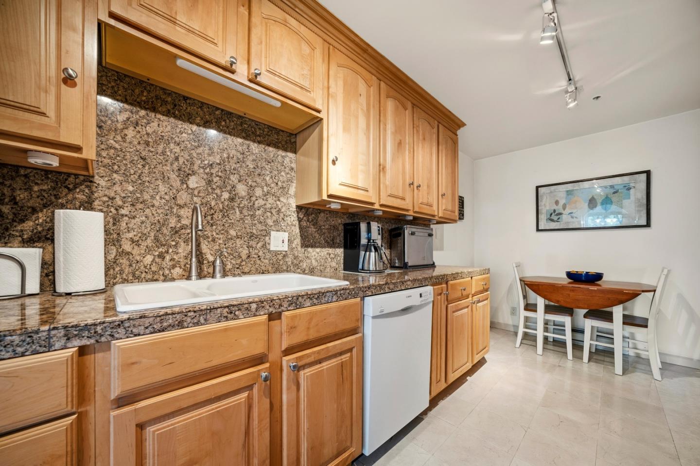 Kitchen with wood cabinets, granite counters, and a small dining table.