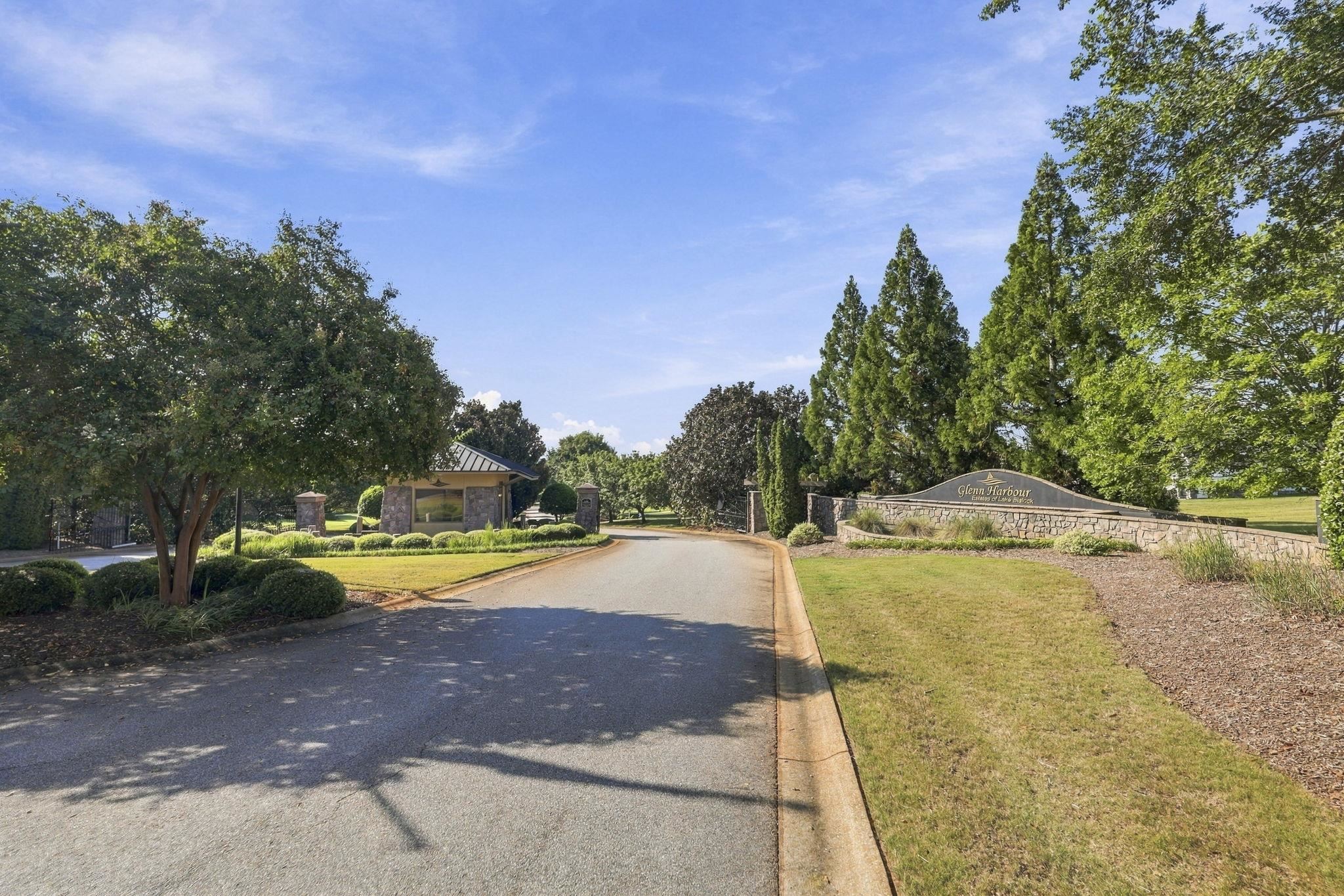 Glenn Harbour community entrance with a curved stone sign, entry pavilion, and tree-lined road.