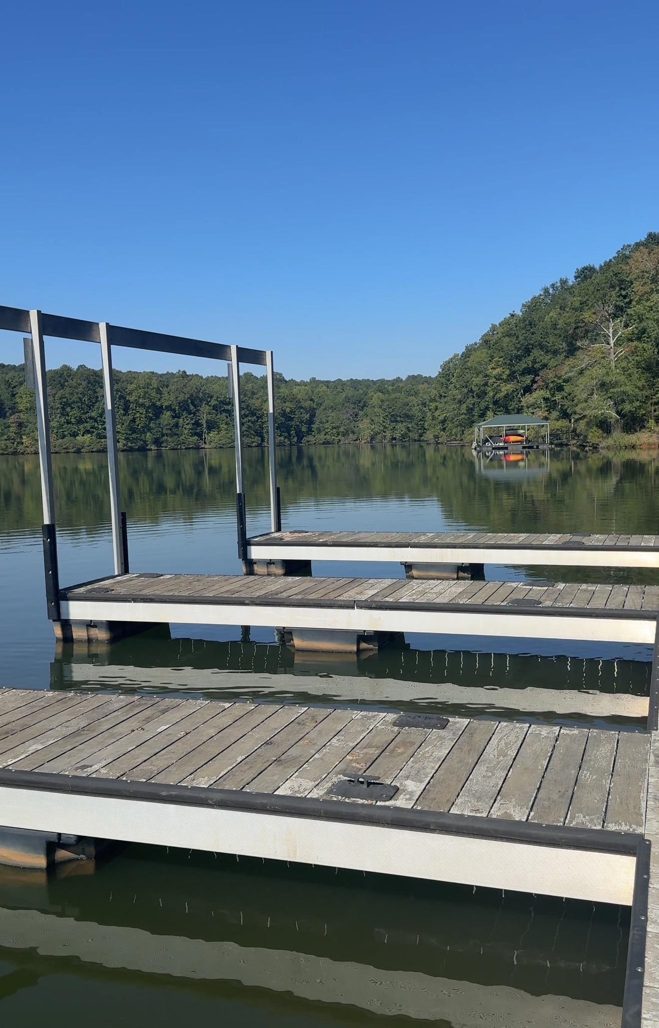 Wooden docks extend over a calm, tree-lined lake toward a covered boat slip.