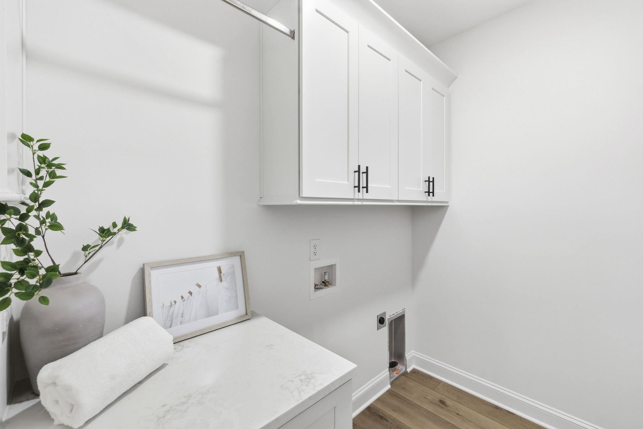 Laundry room with white cabinets, marble-look counter, and washer and dryer hookups.