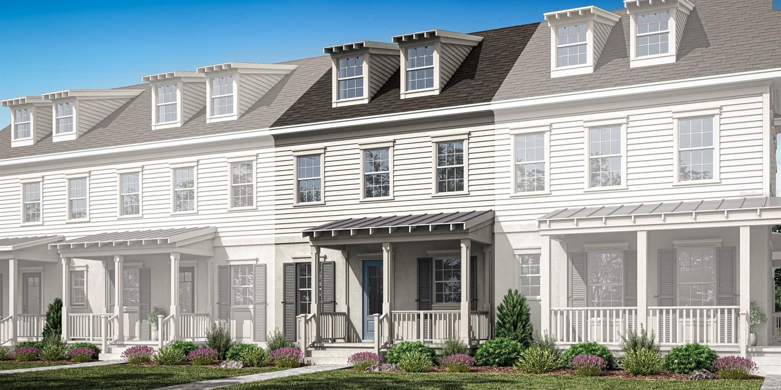 White townhouses with steep gray roofs, dormer windows, covered porches, and landscaped front gardens.