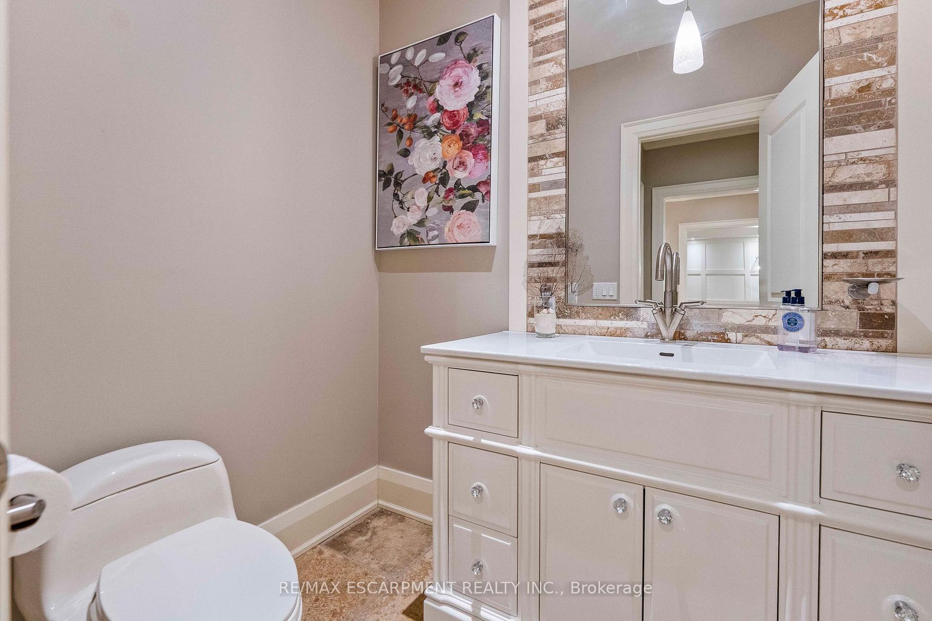 Bathroom with a wide white vanity, marble-patterned backsplash, large mirror, and floral wall art.