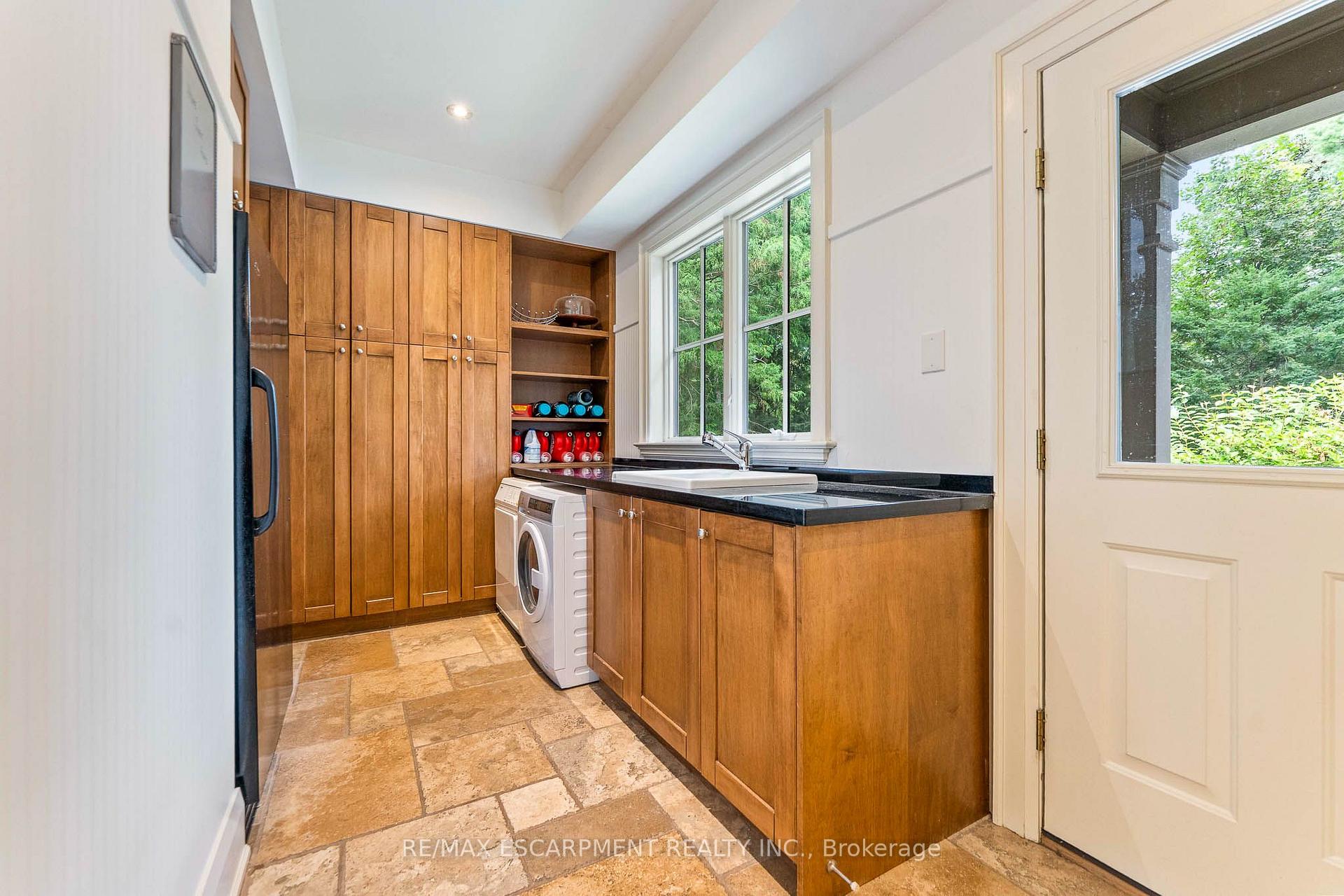 Laundry room with extensive wood cabinetry, a utility sink, and a front-loading washer.