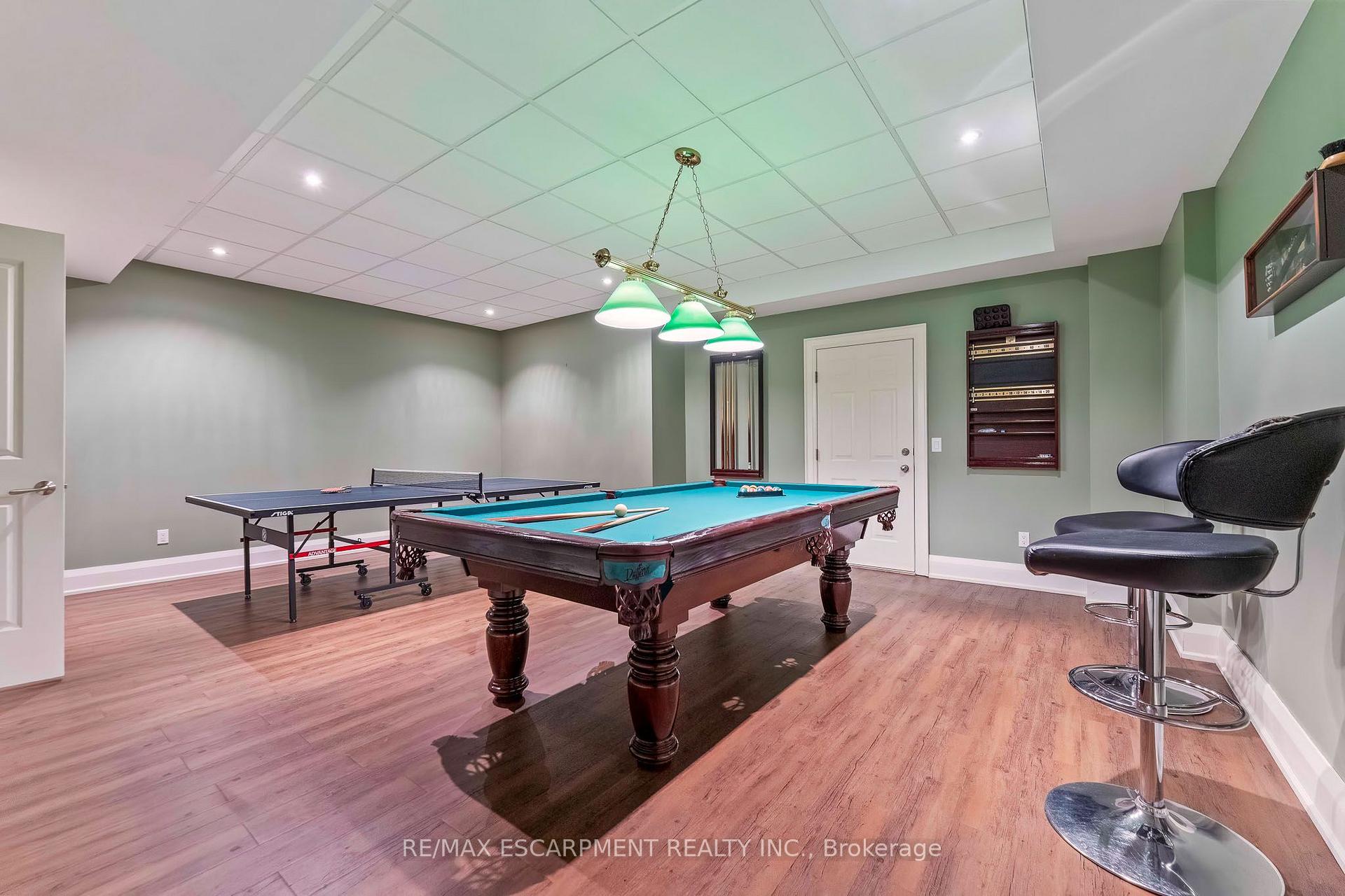 Basement recreation room with a billiards table, table-tennis table, and bar stools.