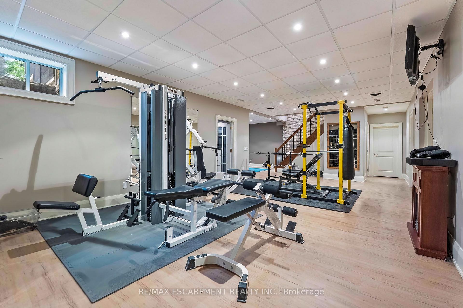 Basement home gym with weight machines, a yellow power rack, and a punching bag.