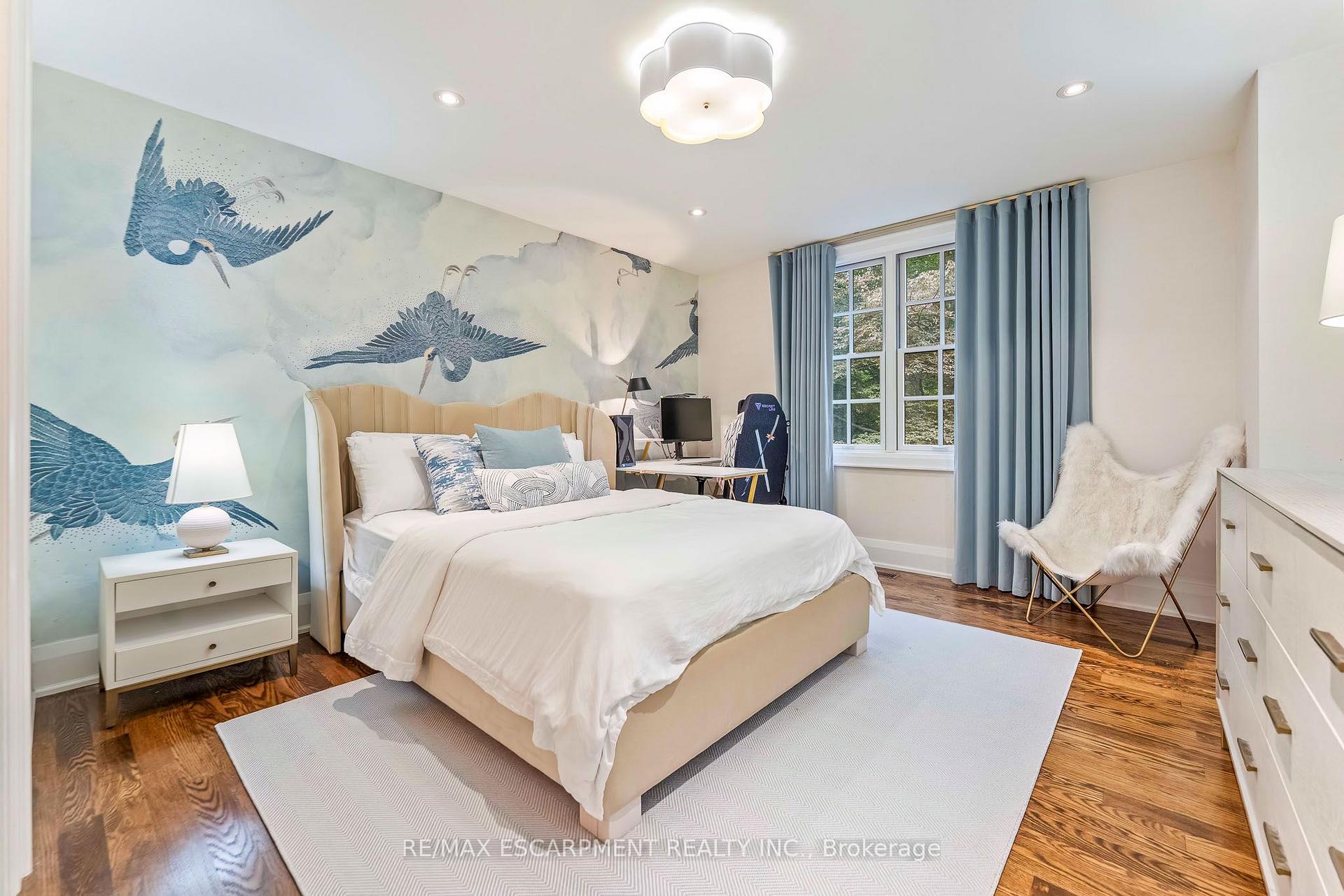 Staged bedroom with a crane mural behind the bed and blue curtains framing a window.