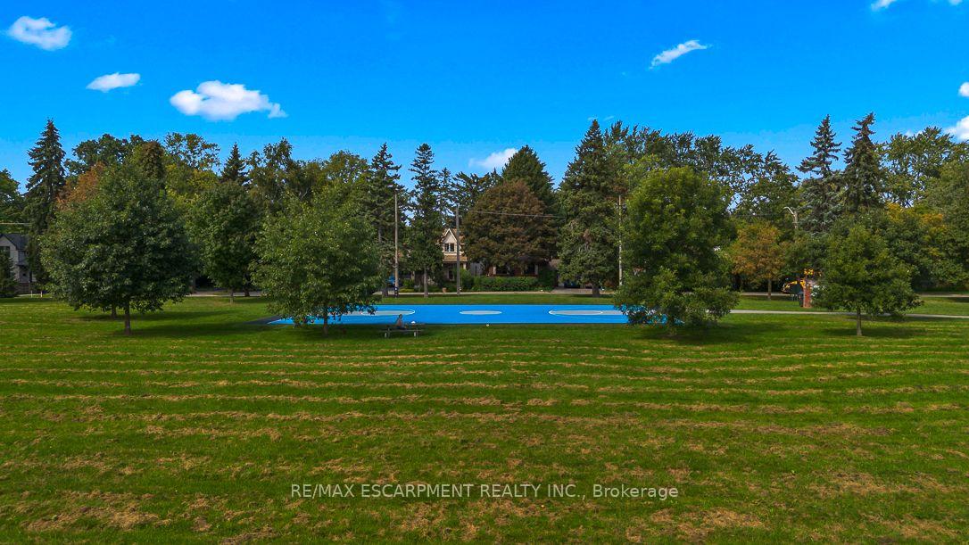 Outdoor swimming pool bordered by mature trees and a broad grassy lawn.