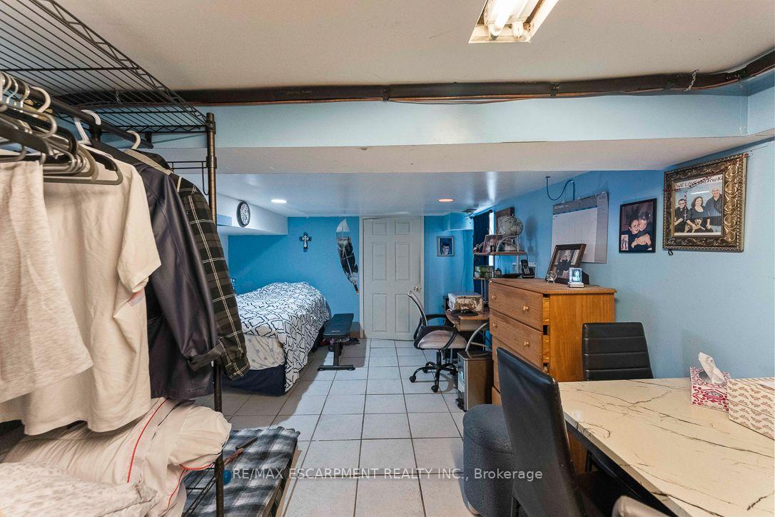 Basement bedroom and workspace with a bed, desk, clothing rack, and blue walls.