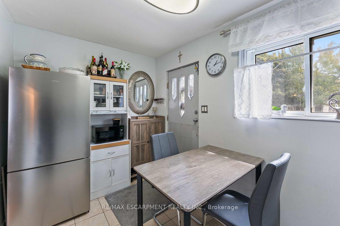 Kitchen dining area with stainless steel refrigerator, built-in cabinets, and a wood-look table by the window.