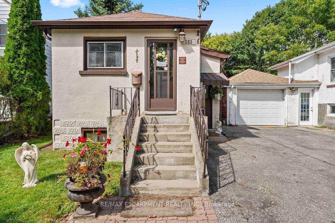 House exterior with concrete front steps, flower garden, and attached garage.