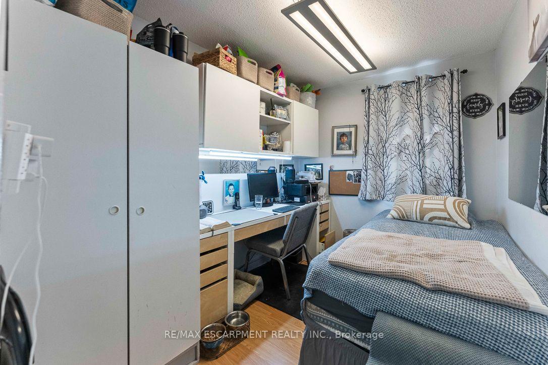Furnished bedroom with a single bed, built-in white cabinets, and a desk workspace.