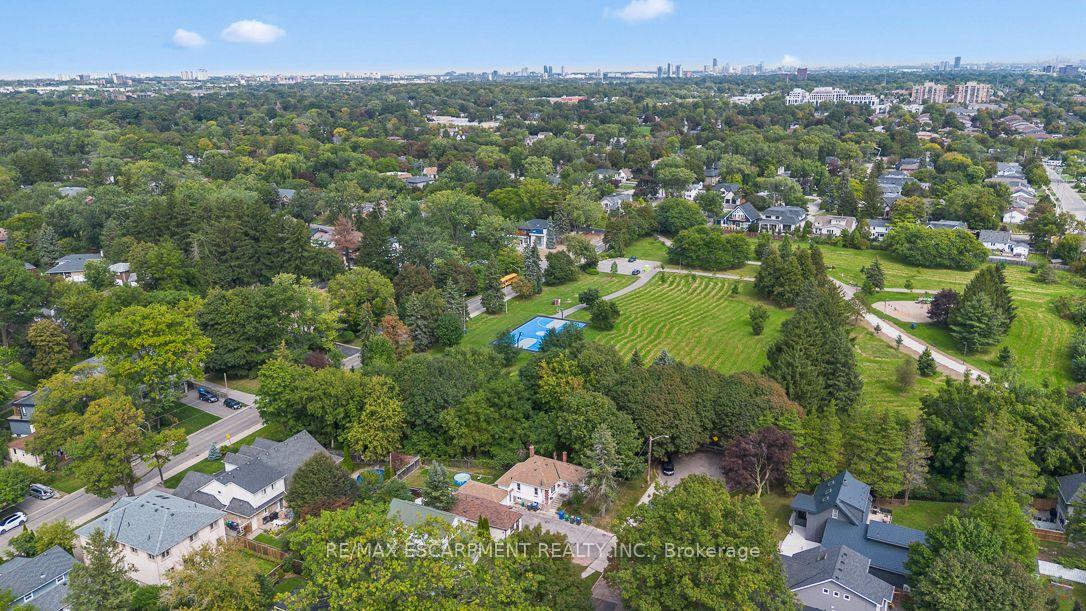 Aerial view of a leafy residential neighborhood, parkland, and distant city skyline.