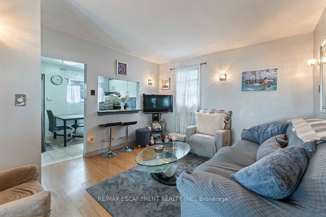 Living room with a gray sectional, glass coffee table, and breakfast bar opening to the kitchen.