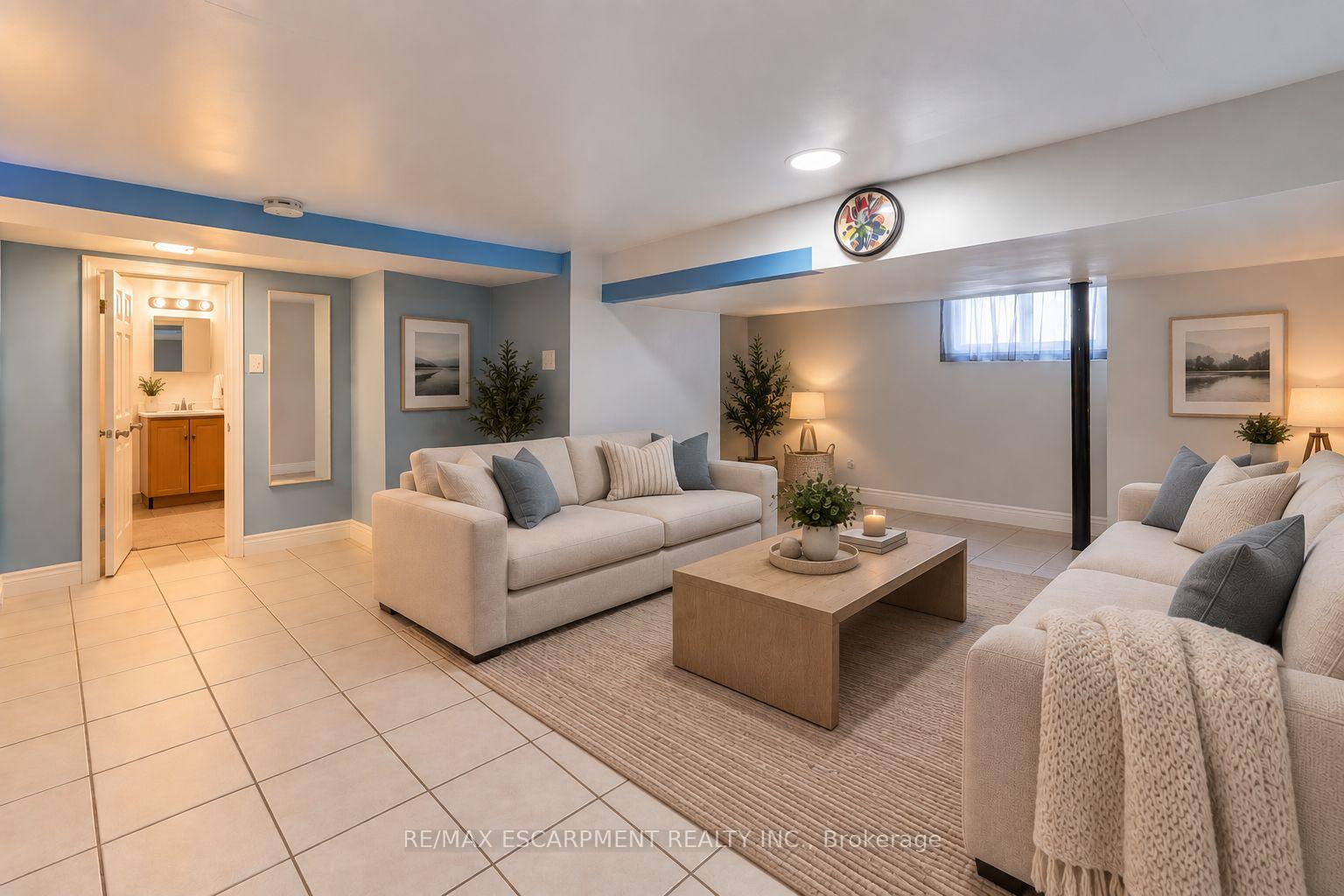 Staged basement living room with cream sofas, a wood coffee table, and a tiled floor.